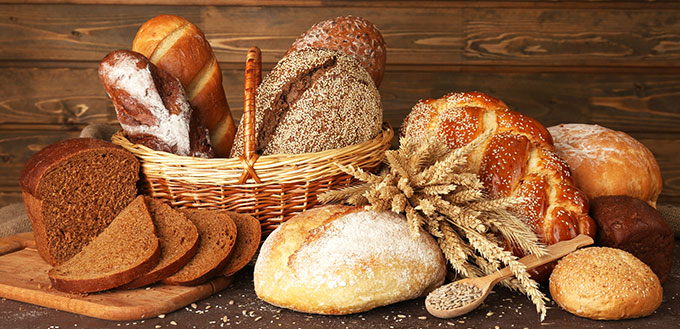 Different bread with ears and sunflower seeds on wooden background