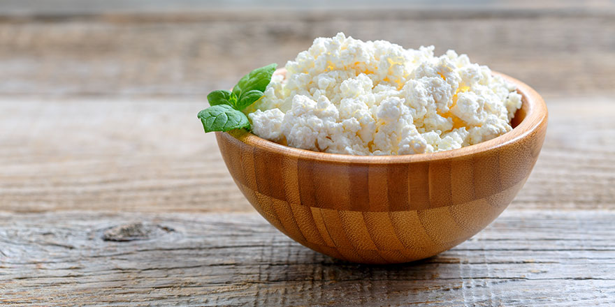 Homemade cottage cheese in a bowl on old wooden table.