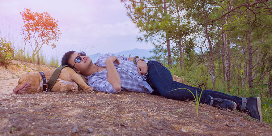 Young man and dog sleeping on the earth road.