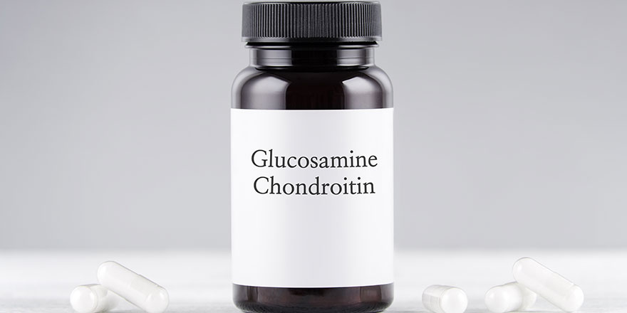 nutritional supplement glucosamine and chondroitin bottle and capsules on a gray background.