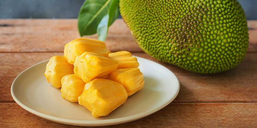 Ripe jackfruit flesh in white-plate on wooden table for-tropical-fruit-or meat substitute concept