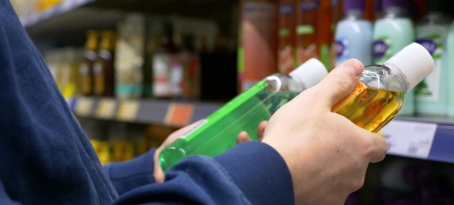 A man in a store chooses a shower gel, carefully reads the composition