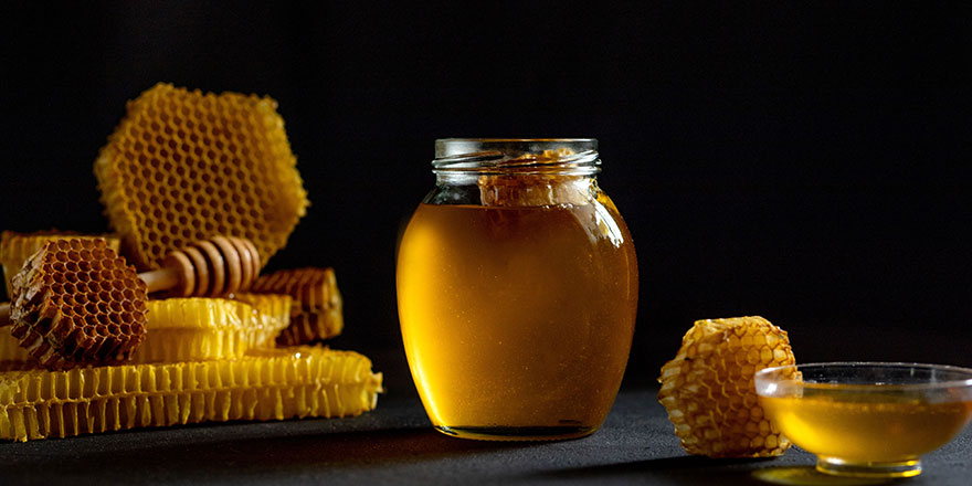 Honey with honeycomb on black table