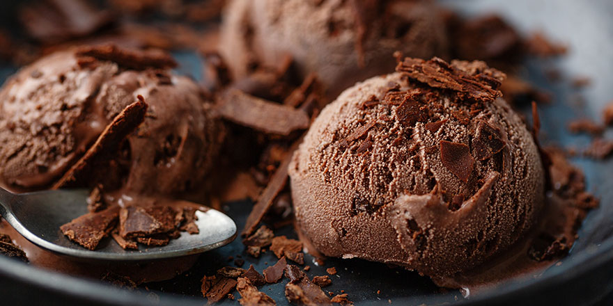 Tasty appetizing chocolate ice cream with chocolate chunks on dark plate on dark background