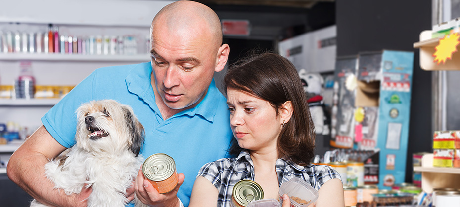 Upset man and woman with dog choosing pet preserves in the pet store