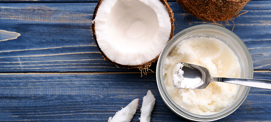 Opened glass jar with fresh coconut oil on wooden background